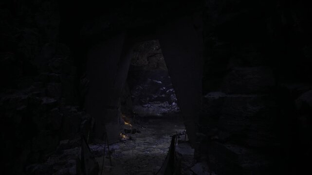Shadowed cavern camp glows with embers, small fire pits arranged near rock walls, map scraps pinned to stone, expedition planning vibe, quiet night