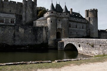 Obraz premium Medieval stone castle with moat and arched bridge, featuring towers and fortified walls
