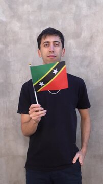 Male adult waving Saint Kitts and Nevis country flag. Vertical slowmo.