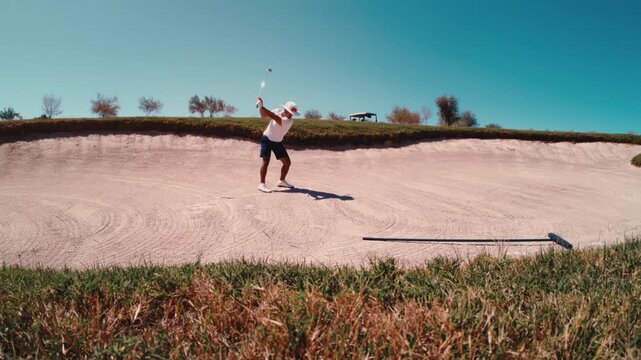 Golfer hits bad shot into lip of fairway bunker, ultra slow motion on sunny day in 4k 800fps