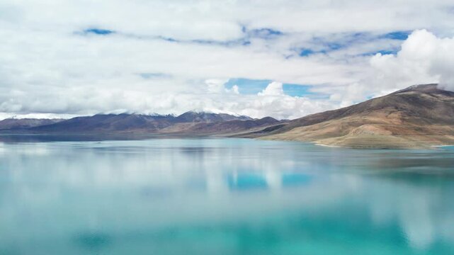 Drone view of Pegu Tso lake or Peikucuo in sunny day in Shigatse, Tibet, China, beautiful peaceful turquoise sea with mountains reflections in Xizang, 4k real time footage travel concept