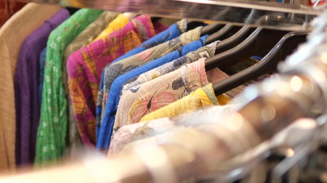 Rack of colorful ethnic shirts and traditional patterned clothing in a boutique store