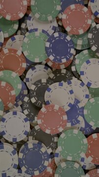 Vertical 4K video panning upward across a pile of colorful poker chips, creating a bright casino gaming background.