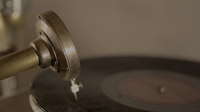 4K slow motion video of a vintage vinyl record spinning on an antique gramophone with warm cinematic lighting and shallow focus.