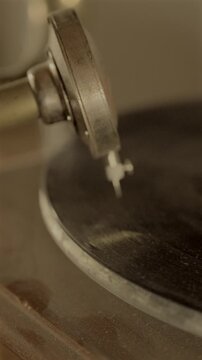 Vertical 4K slow motion video of a vintage vinyl record spinning on an antique gramophone with warm cinematic lighting and shallow focus.