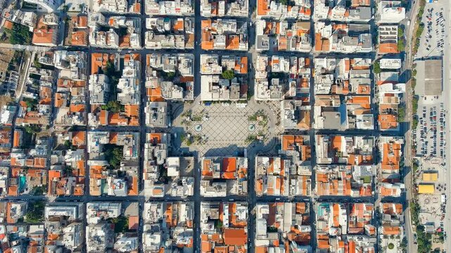 Patras, Greece. Georgiou I Square, neoclassical Apollo Theatre and twin fountains at the heart of a terracotta-roofed grid, Drone footage on a bright summer day. Drone footage, HEAD OVER SHOT