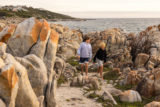 two barefoot boys exploring and hiking the spectacular rocky coastline of DeKeldres, South Africa