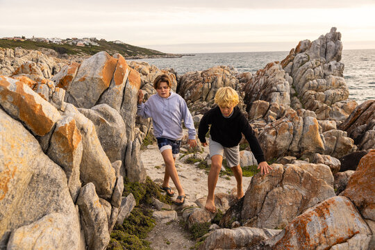 two barefoot boys exploring and hiking the spectacular rocky coastline of DeKeldres, South Africa