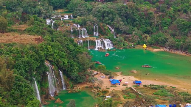 Aerial drone view of Ban Gioc Waterfall with emerald lake and tourist boats, Cao Bang, Vietnam