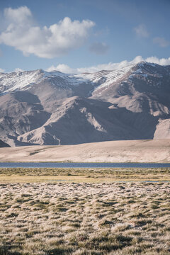 Clear-water rivers and lakes in a mountain valley, pastures and green grassy fields set against mountain ranges and snow-capped, glacier-clad peaks&mdash;a scenic landscape background