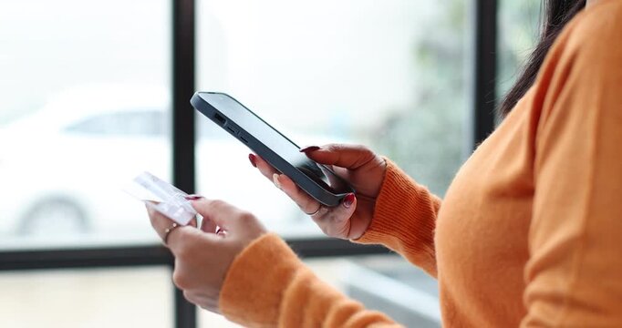 Asian woman talking on smartphone and holding credit card, showing online shopping concept with secure transactions, digital payment, and e commerce services