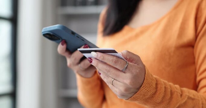 Asian woman talking on smartphone and holding credit card, showing online shopping concept with secure transactions, digital payment, and e commerce services