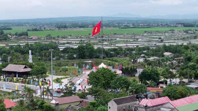 Panoramic aerial view reveals vast green rice paddies stretching across the flat landscape of the former DMZ area in Quang Tri, with the Vietnamese flag visible in the distance.