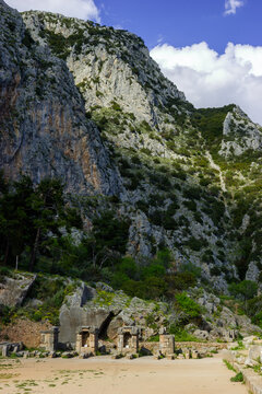 Ancient ruins of Delphi, Greece, with rocky mountains and blue sky.