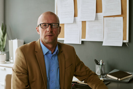 Portrait of middle aged Caucasian man sitting in office, looking at camera, representing corporate leadership and professional communication. Useful for business consulting marketing