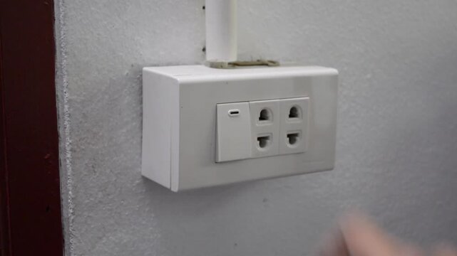 Close-up of a hand turning an electric light switch on and then off at the end