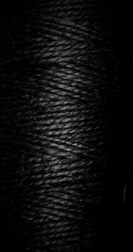 Black Twine Fiber Texture. Macro view of tightly wound coarse strands under a narrow light beam. For dark abstract backgrounds.