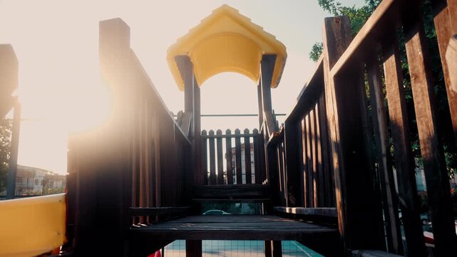 Bright morning light shines on a wooden playground structure in an outdoor park setting during early hours