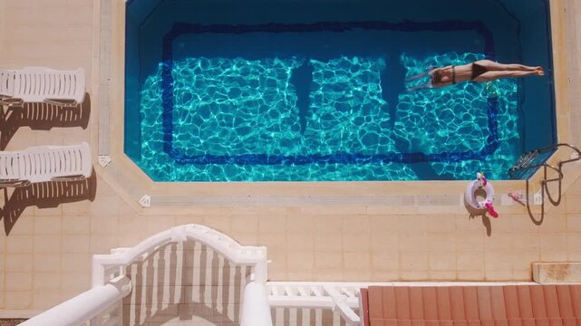 Swimming in a pool during a sunny day while relaxing on a float with lounge chairs nearby
