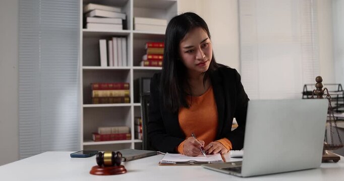 Professional asian lawyer working on litigation cases using a laptop in a modern law office representing justice, legal services, and online consultation for clients focusing on legal advice