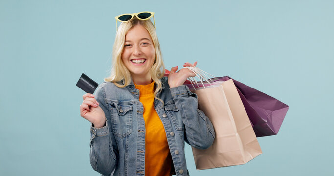 Happy, girl or shopping bags with credit card in studio for fashion budget, retail sale or space. Portrait, shopper or cashless purchase on blue background for reward points, loyalty program or gifts