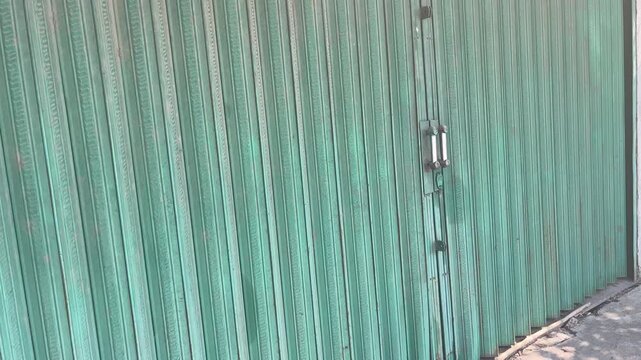 Closed and locked green rolling door of a local shop