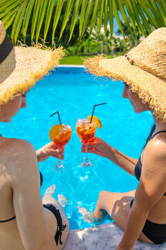 Friends drinking cocktails by the pool. Selective focus.