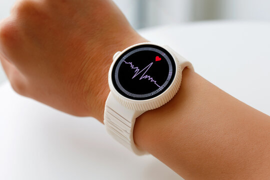 Close up of young woman arm with round plastic white smartwatch showing heart rate pulse data and graph, health and fitness tracking digital connected watch