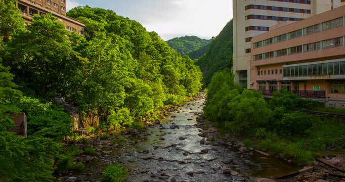Jozankei Onsen River Day Timelapse: Toyohira River with Lush Green Mountains and Hot Spring Hotels, Sapporo, Hokkaido, Japan - Wide Angle Shot
