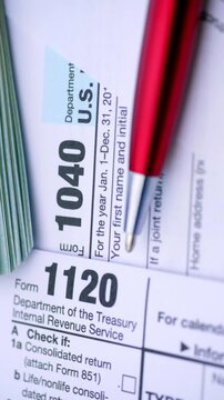 US Tax Forms and Dollar Bills. Close-up view of income tax documents with cash and a red pen during smooth camera movement.