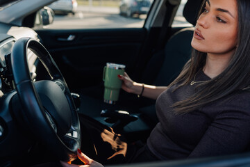 Fototapeta premium Woman driving car holding insulated cup commuting