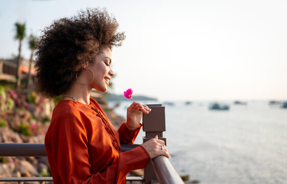 Stylish traveler woman relaxing at a seaside resort, enjoying the scenic tropical view at dusk