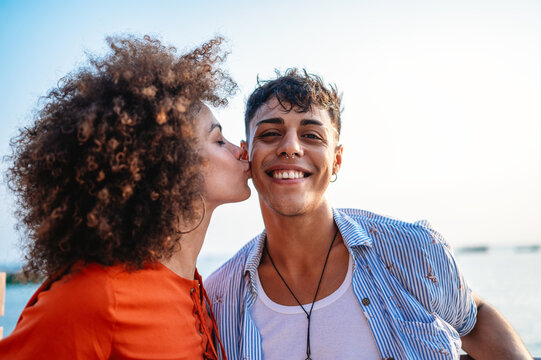 Happy romantic couple kissing on the beach at sunset. Diverse man and woman in love