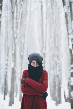 Woman in red coat feeling cold in winter snow