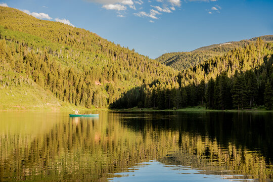 Person fishing from a canoe on a still lake