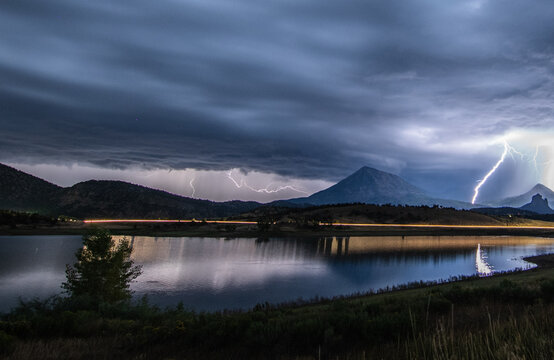 Lightning flashes over a lake and mountains at night