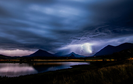 Dramatic lightning strike over mountains at night
