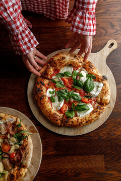 A young woman takes a slice of freshly baked pizza.