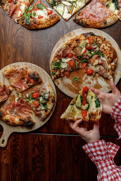 A young woman takes a slice of freshly baked pizza.