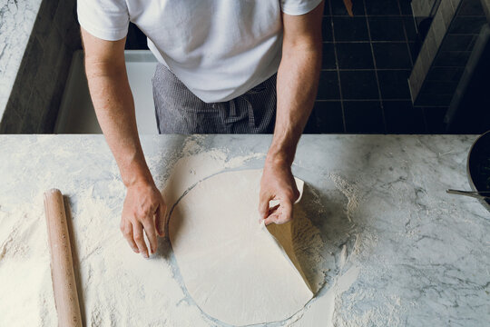 A pizzaiolo rolls out dough for artisanal pizza. Isolated.
