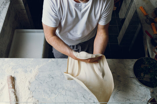 A pizzaiolo juggles dough and shapes it into a pizza.