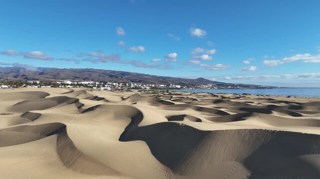 Aerial panorama flight over Maspalomas Dunes with hotels in Playa del Ingles, beach, Atlantic ocean and mountains on Canary Island Gran Canaria, Spain
