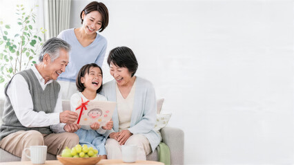 孫の手作りカードを囲んで笑う祖父母と母親