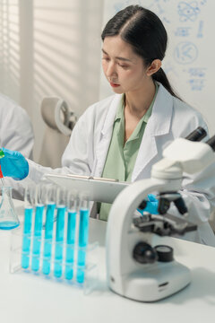 Woman researcher adjusting separating funnel and analyzing test tubes in lab.