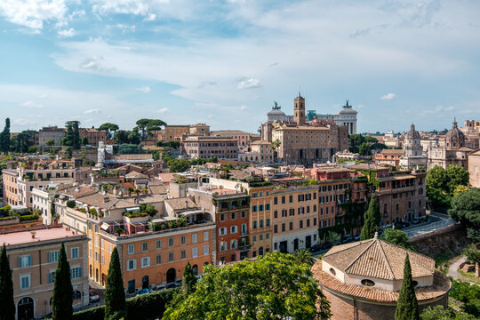 Scenic high angle view over the colorful historic rooftops and buildings of Rome, Italy towards the Campidoglio and Altare della Patria under a bright sky