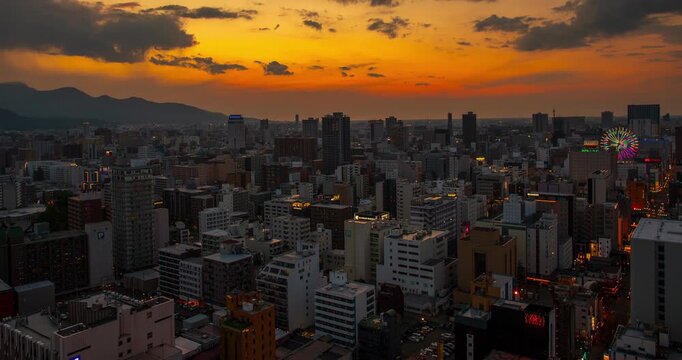 Sapporo, Hokkaido downtown city skyline view with a colorful sunrise dawn sky transitioning from dark morning to bright early daylight over urban buildings
