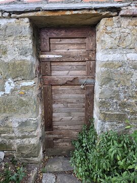 Rustic old wooden door with padlock in a historic stone wall