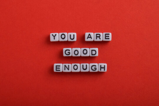 You are good enough spelled with letter beads on a red background, representing self esteem, confidence, encouragement, positivity, mental health, and personal growth.