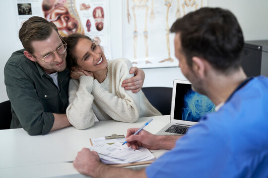 Happy couple with doctor discussing over prescription in clinic