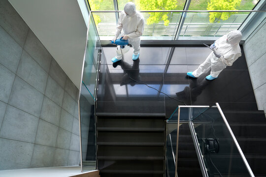 Sanitation workers disinfecting staircase in office